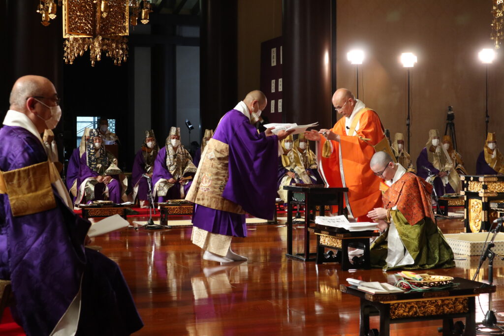4月6日、増上寺での叙任式。川中総長（右）から進叙任者に辞令が手渡された